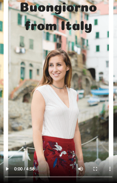 Buongiorno from Italy - Elise Darma smiling in front of colourful buildings.