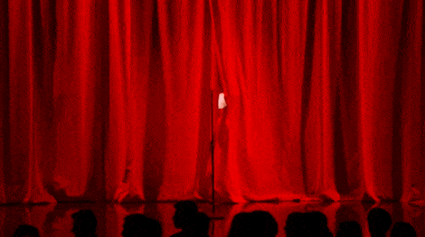 Ariana Grande throwing open a red curtain on a stage.